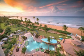 A resort with a large pool, palm trees, and a beach view.