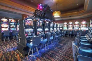 Un casino doté de nombreux appareils à sous, de tabourets de bar et d’un tapis à motifs.
