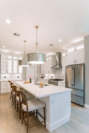 A modern kitchen with a large island, stainless steel appliances, and pendant lighting. - Gorgeous new-build featured in Houston's Most Beautiful Homes of 2023 (Galveston)