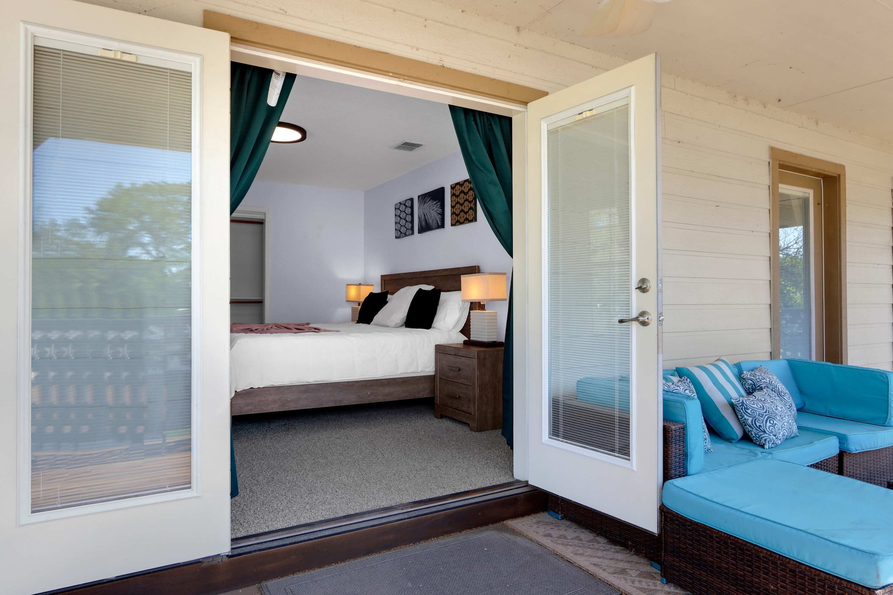 A bedroom with a bed, bedside table, lamp, and a view of the outside. - Spacious Retreat & Game Room Sleeps 12 (New Braunfels)