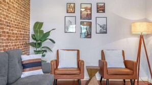 A living room with a brick wall, two leather armchairs, a grey sofa, and a floor lamp. - Spacious Retreat & Game Room Sleeps 12 (New Braunfels)
