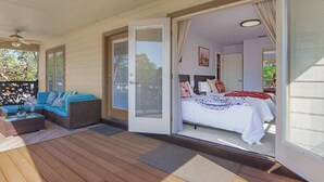 A room with a bed, a sofa, and a sliding glass door leading to an outdoor area with a wooden deck. - Spacious Retreat & Game Room Sleeps 12 (New Braunfels)