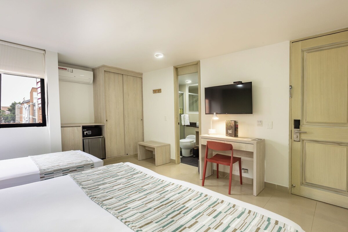 Una camera d'albergo con un letto, una scrivania con una sedia, una televisione e un armadio.