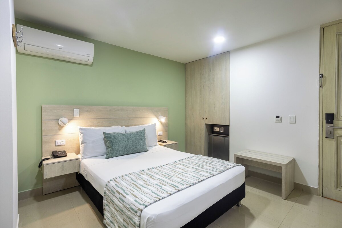 Une chambre à coucher bien rangée, avec un lit, des tables de chevet, une commode, un banc et une armoire.