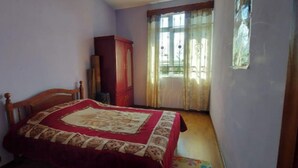 Ein Schlafzimmer mit einem Bett, einem Kleiderschrank und einem Fenster mit Vorhängen.