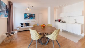 A modern living room with a round dining table, two quilted chairs, a white sofa, and a painting on the wall. - Castalia Apartments & Rooms (Taormina)