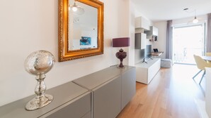 A modern living room with a large mirror, a decorative globe, and a purple lamp on a grey console. - Castalia Apartments & Rooms (Taormina)