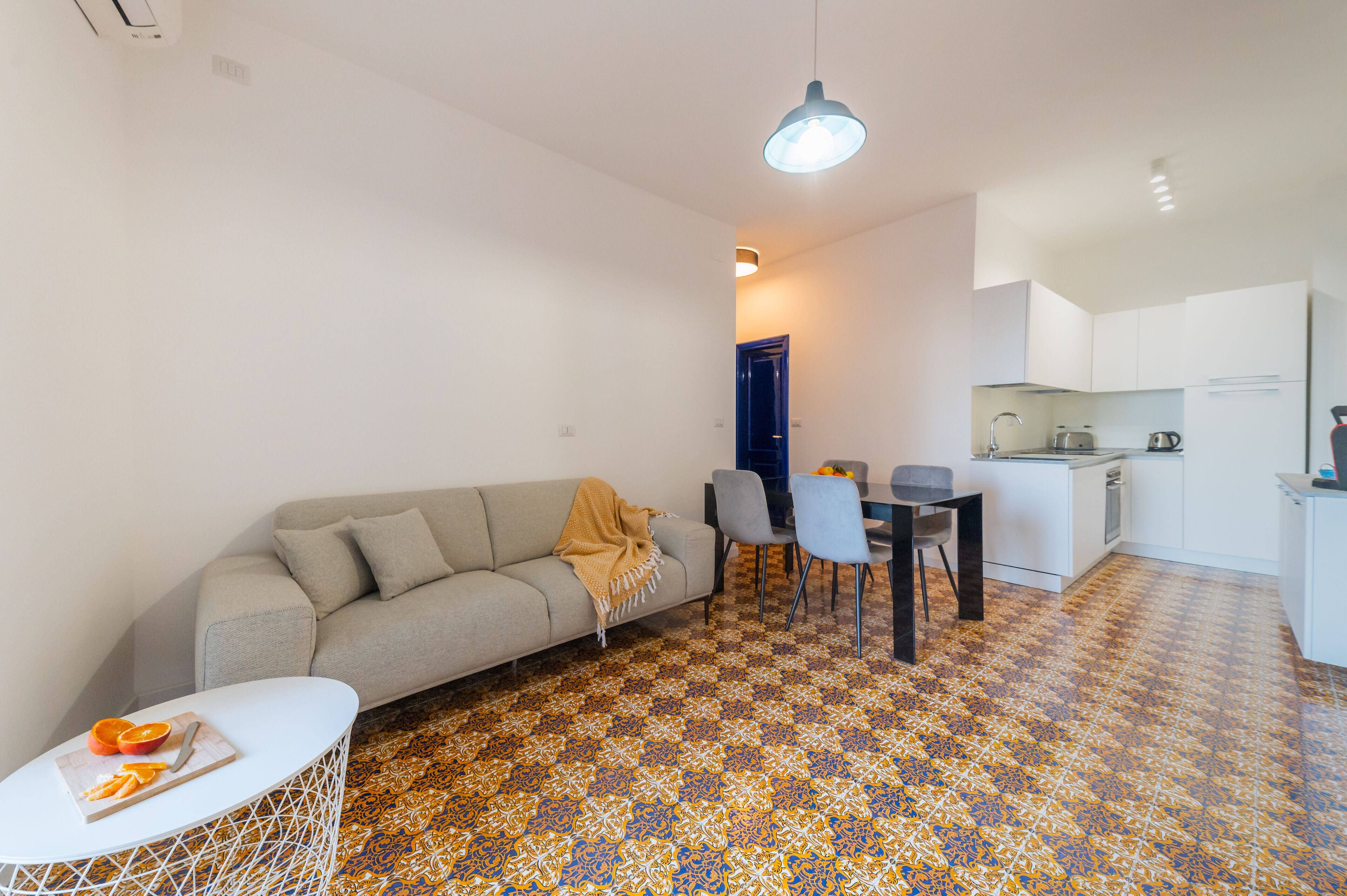 Un espacio habitable compacto con sofá, mesa de comedor, sillas y kitchenette.
