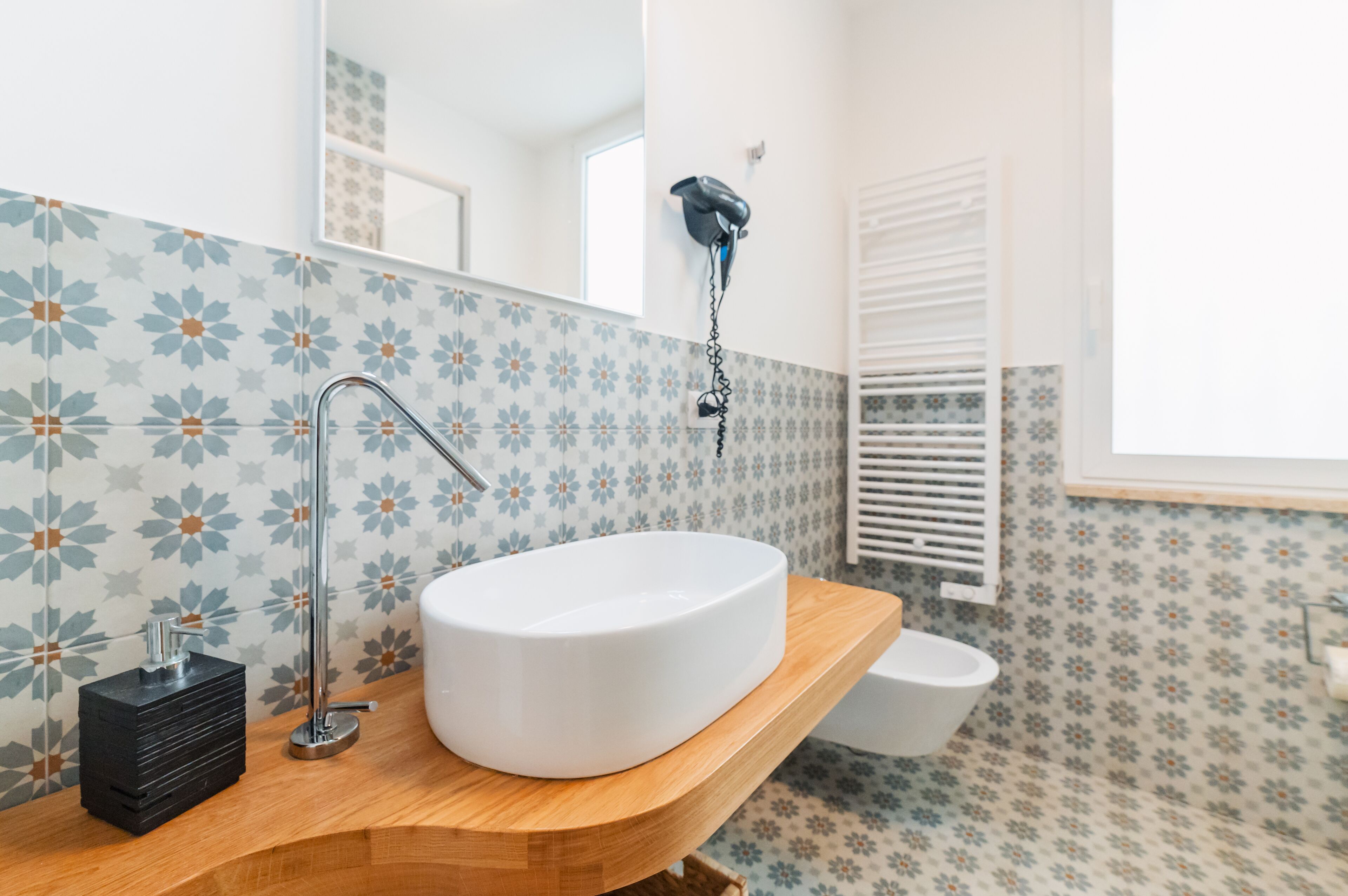 Un baño con un lavamanos blanco, encimera de madera y un espejo.