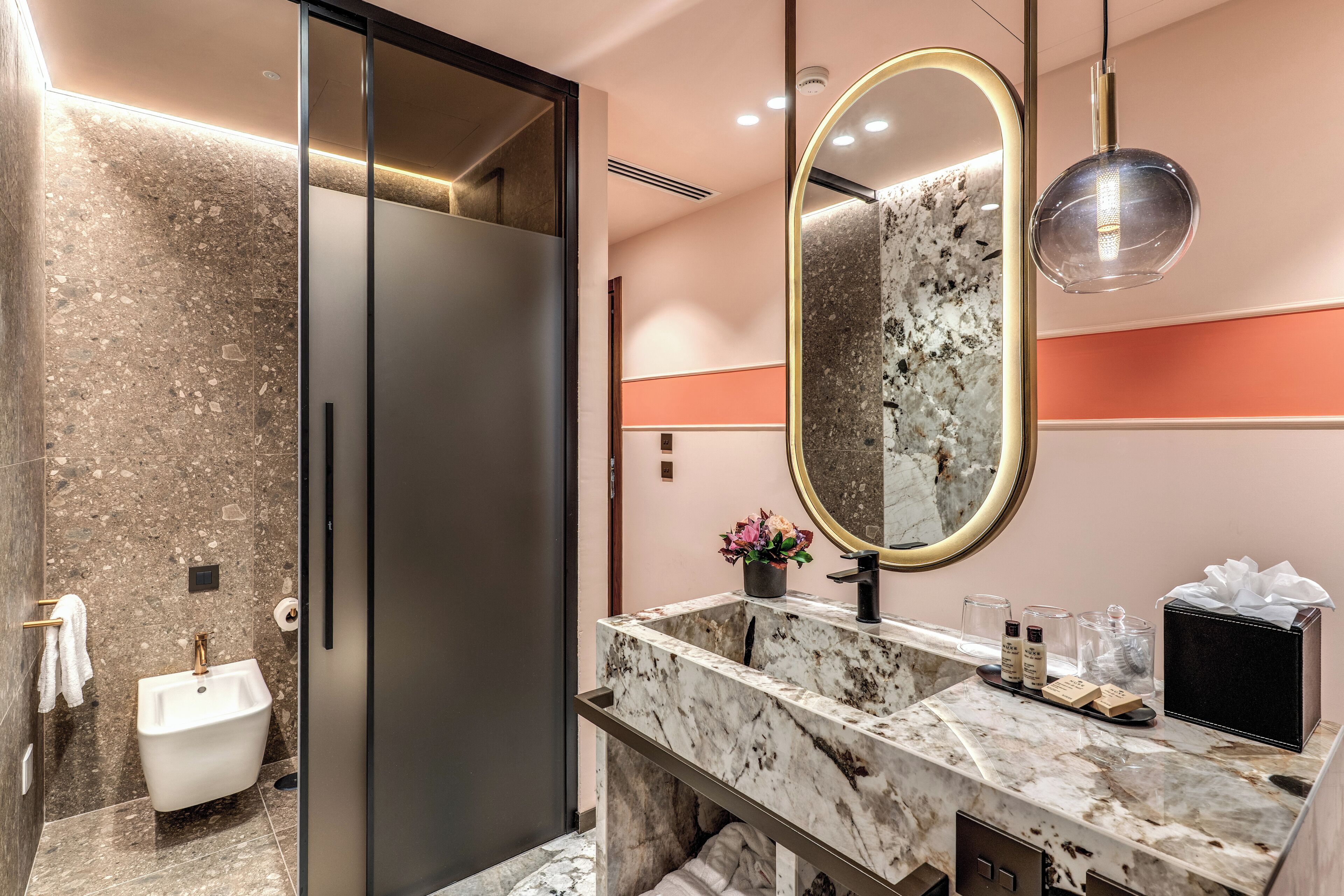 Un bagno moderno con un lavabo in marmo, uno specchio grande e un porta asciugamani.