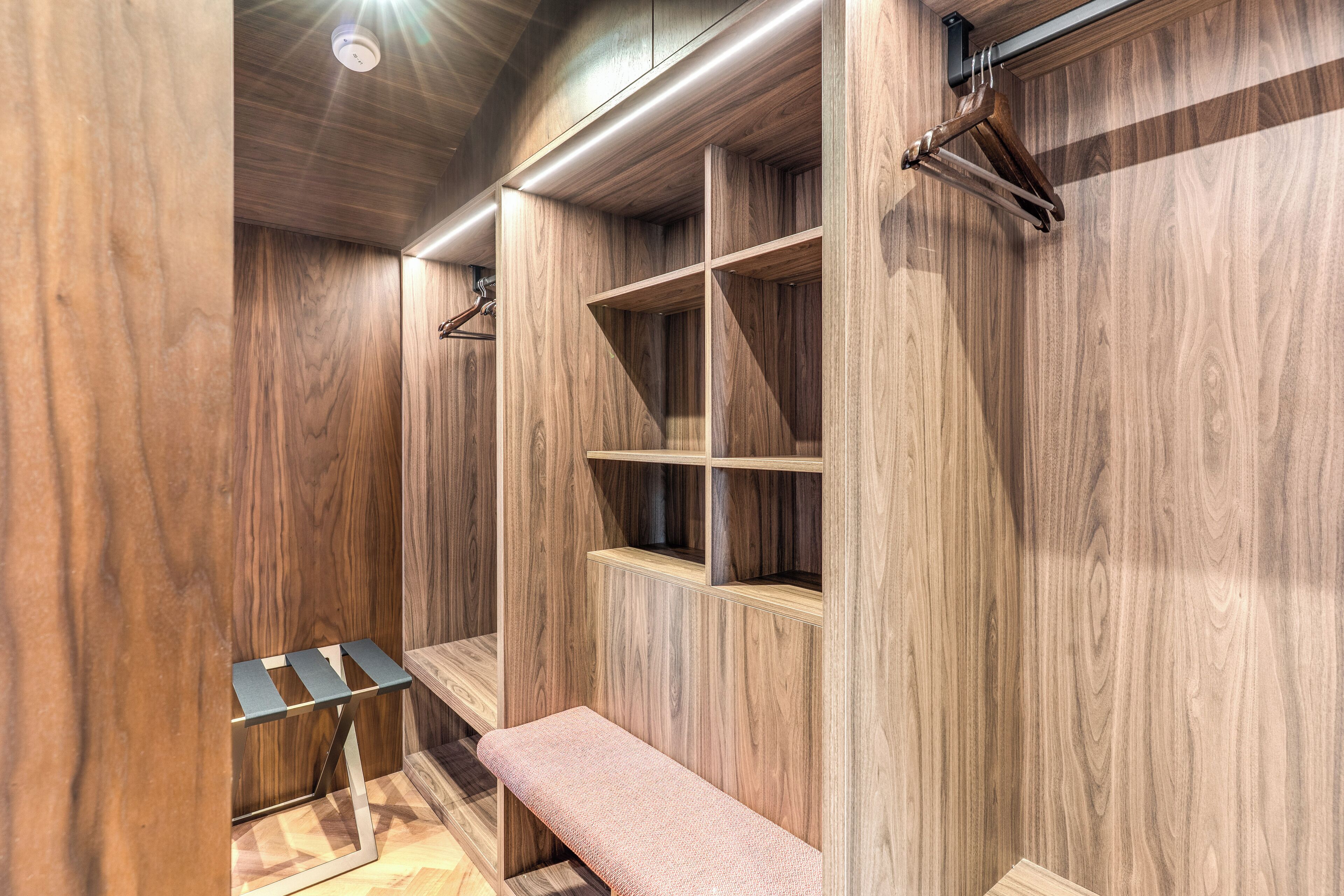 Un vestidor con paneles de madera, estantes y un banco.