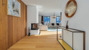 A modern living room with a wooden floor, a white sofa, and a large painting on the wall.