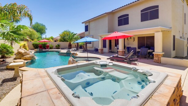 Ein Garten mit Schwimmbad, Whirlpool und Sitzbereich im Freien mit Sonnenschirmen.