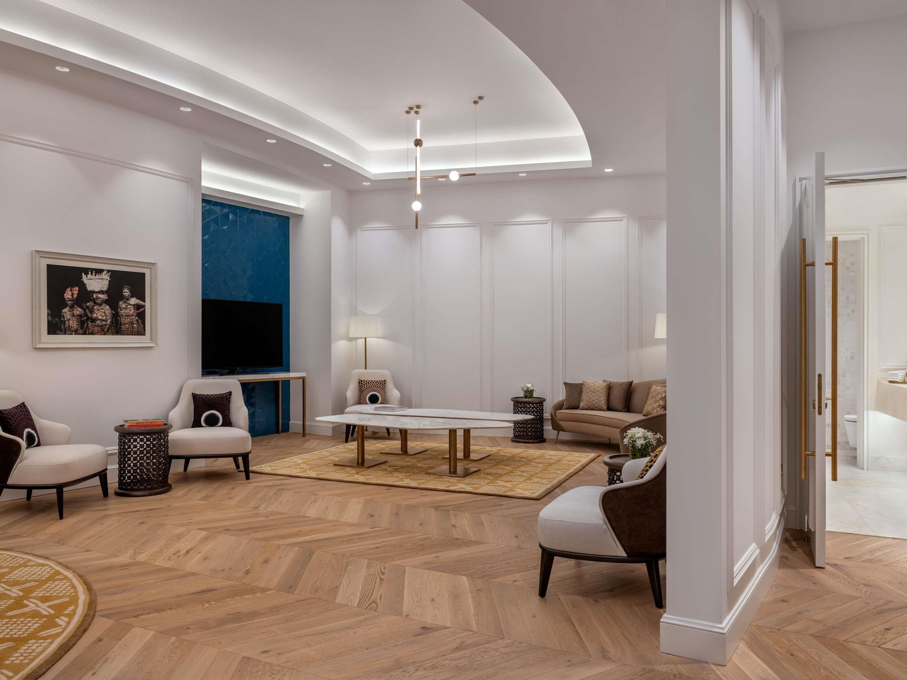A modern living room with a white ceiling, a large TV, a sofa, a coffee table, and a patterned rug.