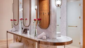 Un baño moderno con encimeras de mármol, varios espejos, un mueble de madera y un lavabo redondo.