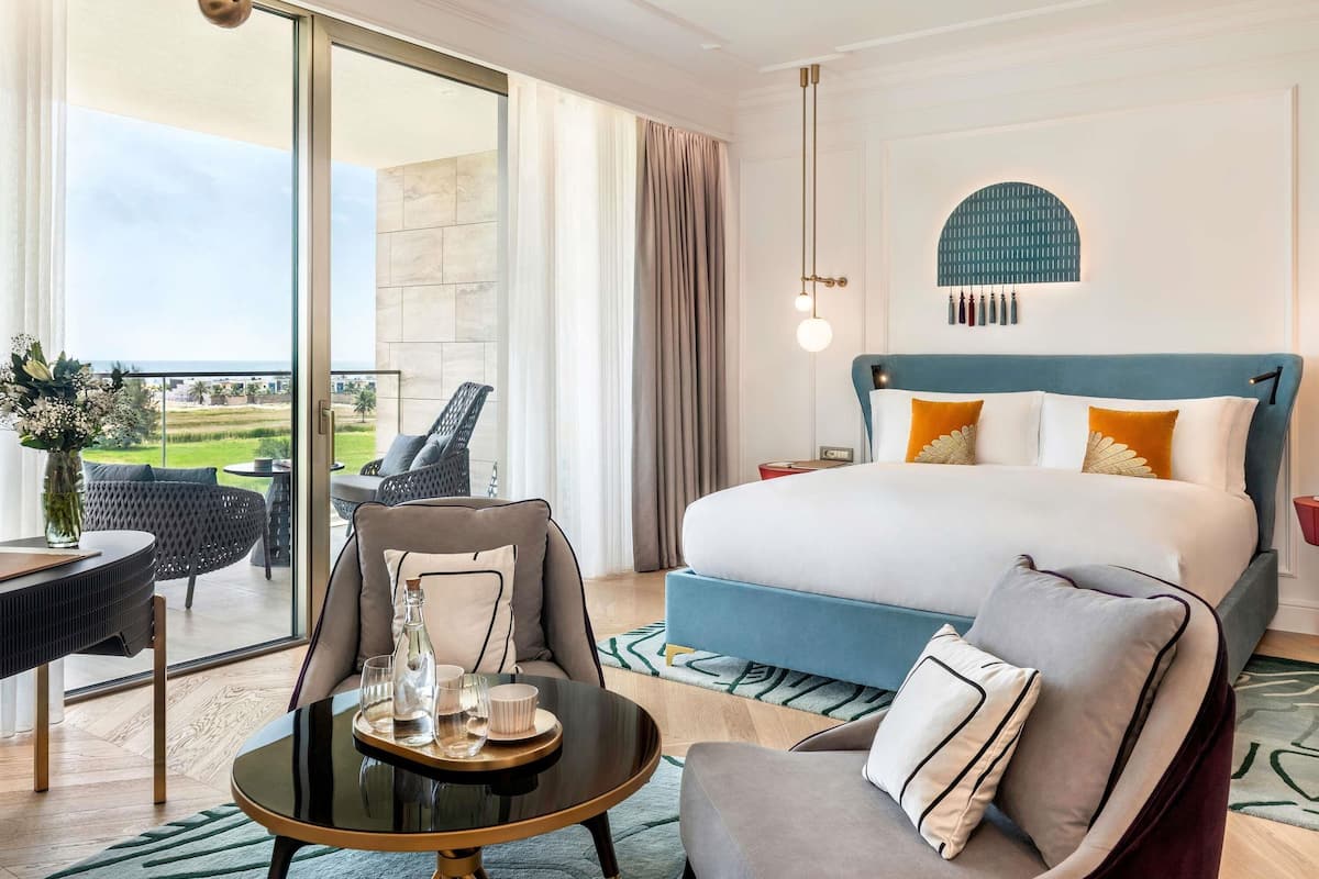 Een hotelkamer met een bed, een eettafel, een stoel en uitzicht op het omliggende landschap.