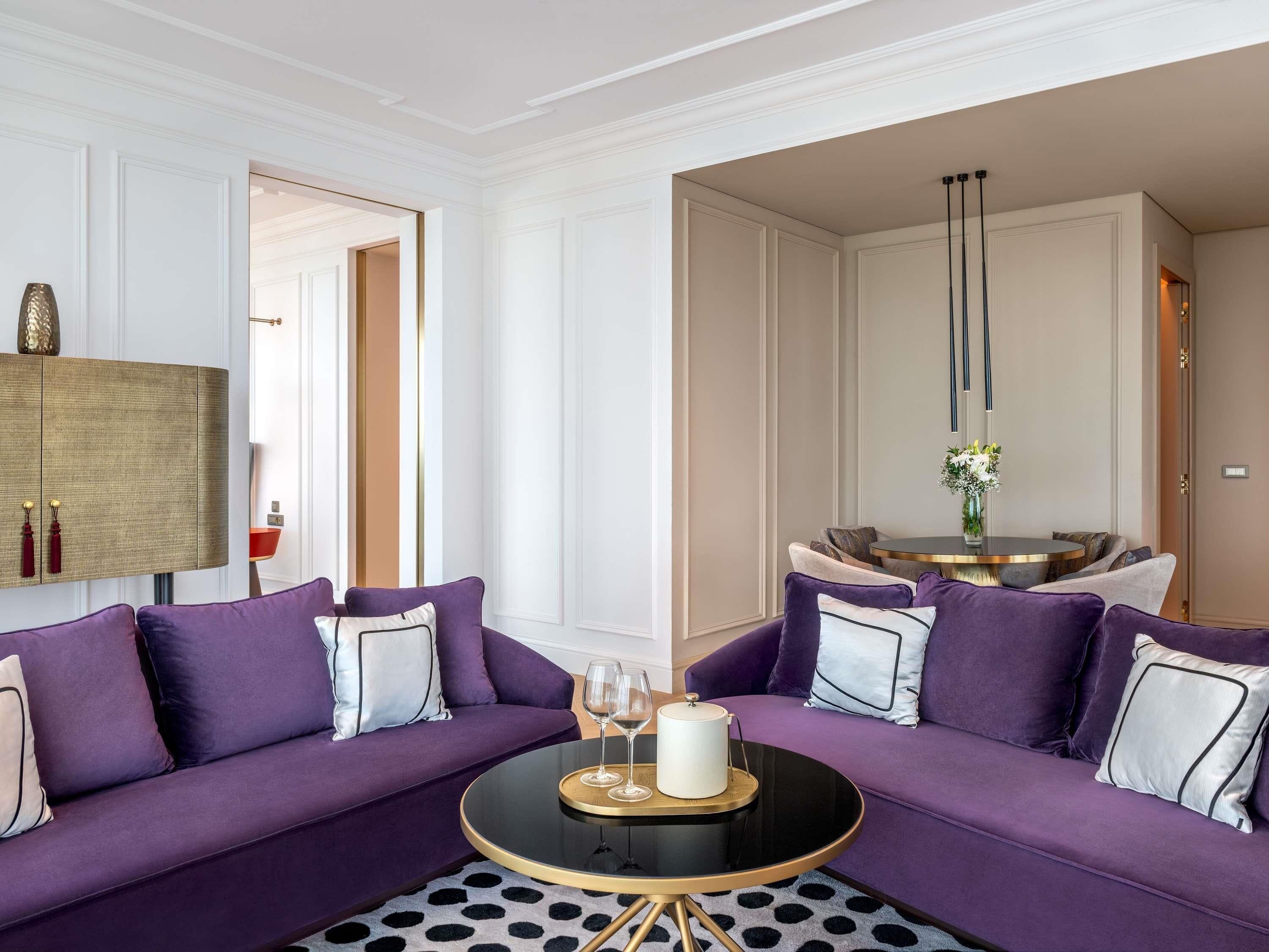 A modern living room with a purple sofa set, a round black coffee table, and a minimalist decor style.