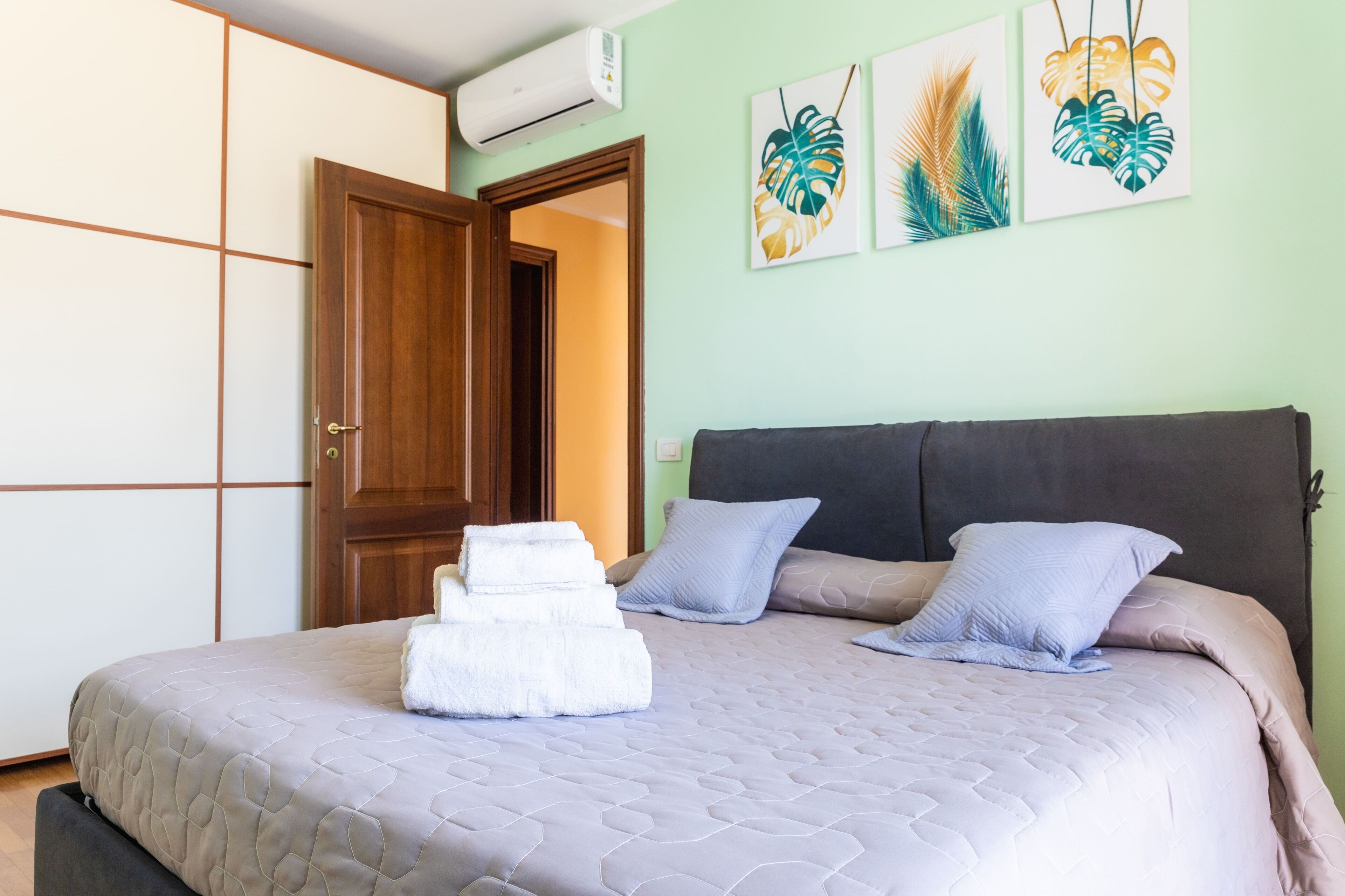 A bedroom with a bed, pillows, a bedside table, and a wardrobe.