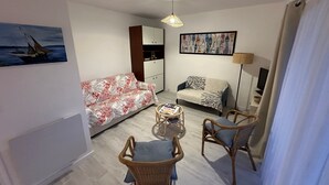 Una sala de estar con un sofá, dos sillones, una mesa de centro, una lámpara y un cuadro en la pared.
