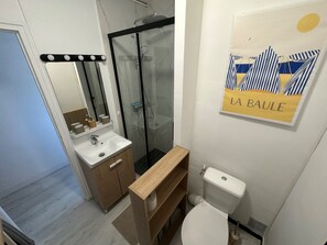 A bathroom with a shower, toilet, sink, and a mirror. - Studio with balcony - 2 min beach and AquaBaule (La Baule-Escoublac)