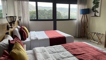 Ein Hotelzimmer mit zwei Betten, einem großen Fenster mit Blick auf die Landschaft, einer Stehlampe und einem Bild an der Wand.