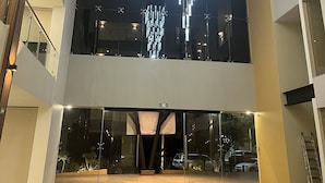 Un edificio moderno con una amplia entrada de vidrio, un candelabro llamativo y un interior de varios niveles.