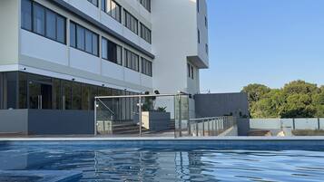 A modern building with a swimming pool in front.