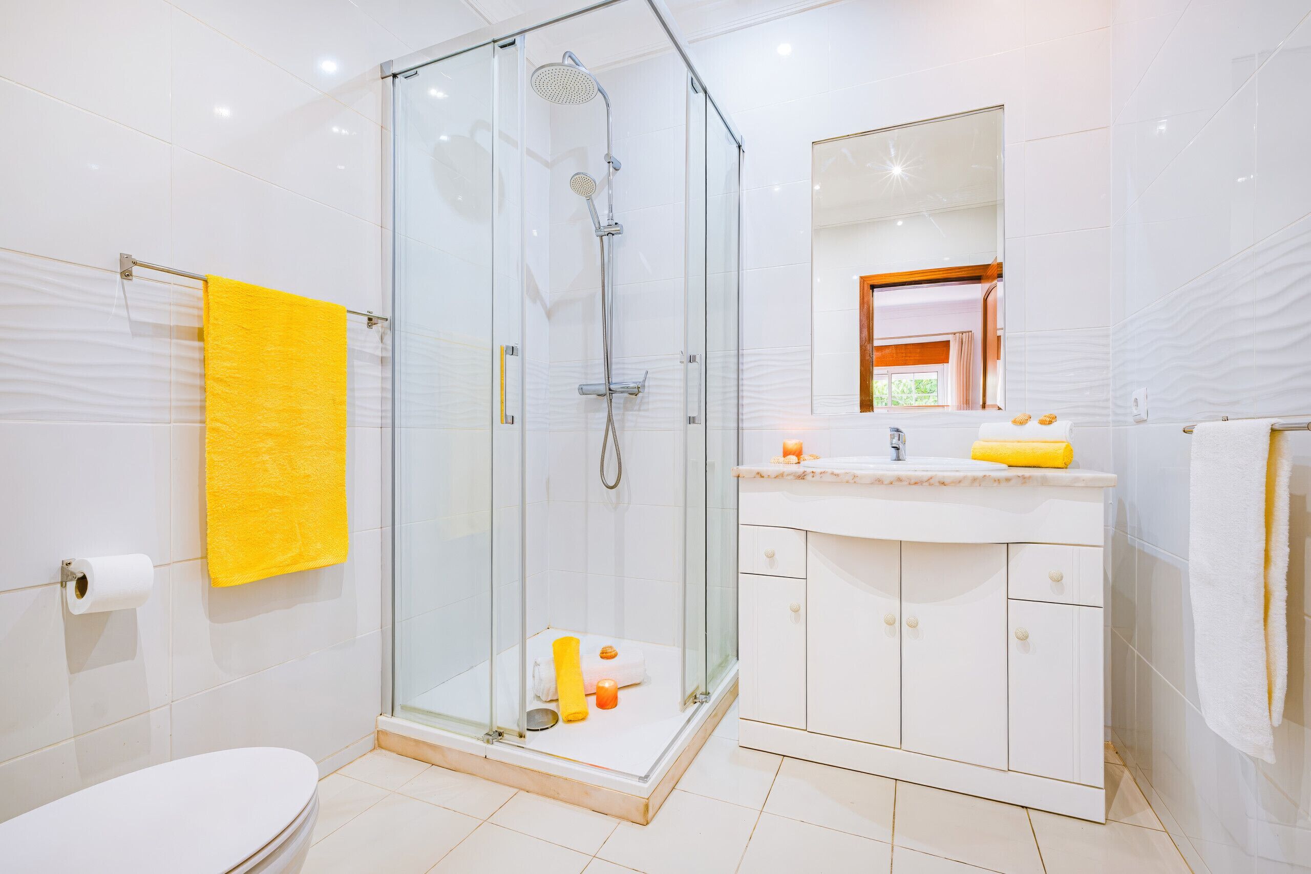 A modern bathroom with a glass-enclosed shower, a white toilet, and a vanity with a mirror.