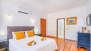 Quarto de hotel com cama, piso de madeira, guarda-roupa e porta para um banheiro.