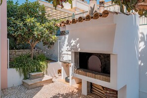 Un cortile con pavimento in pietra, una piccola zona salotto all'aperto e un forno per pizze.