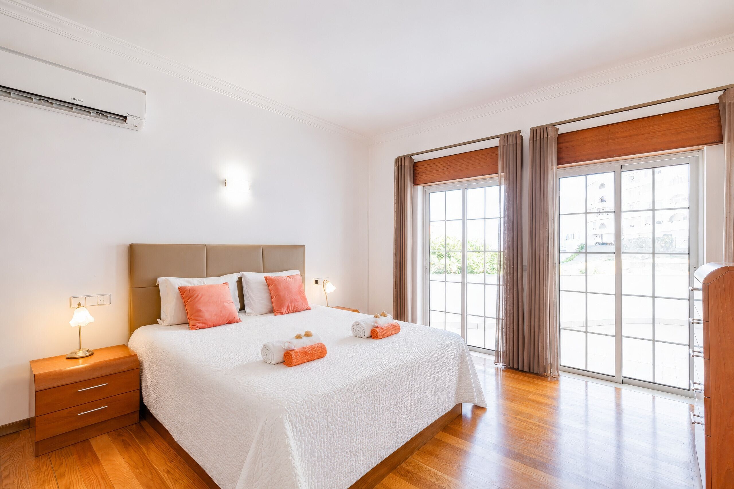 A hotel room with a large bed, a nightstand, a lamp, and a window with curtains.