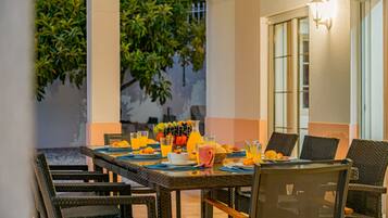 An outdoor dining area with wicker chairs and a table set for breakfast.