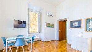 Ein Essbereich mit Tisch und Stühlen, einem an der Wand befestigten Fernseher und einer Klimaanlage.