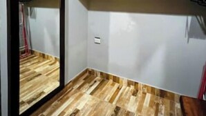Una habitación con suelo de parqué de madera, un espejo grande y estantes empotrados.