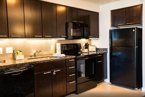 Fully equipped kitchen with a microwave, oven, refrigerator, and sink.
