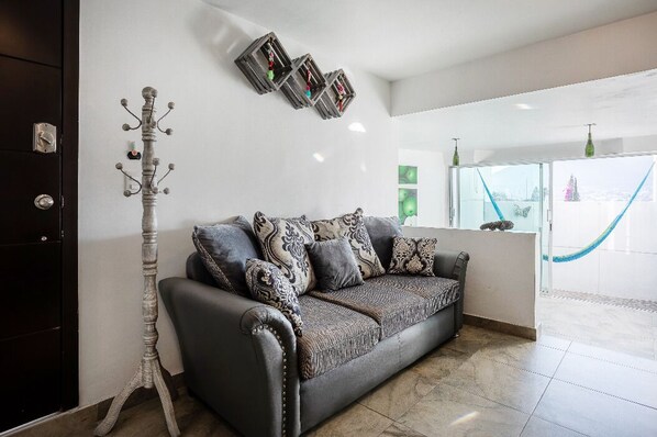 A modern living room with a dark grey sofa, patterned cushions, and a decorative floor lamp.