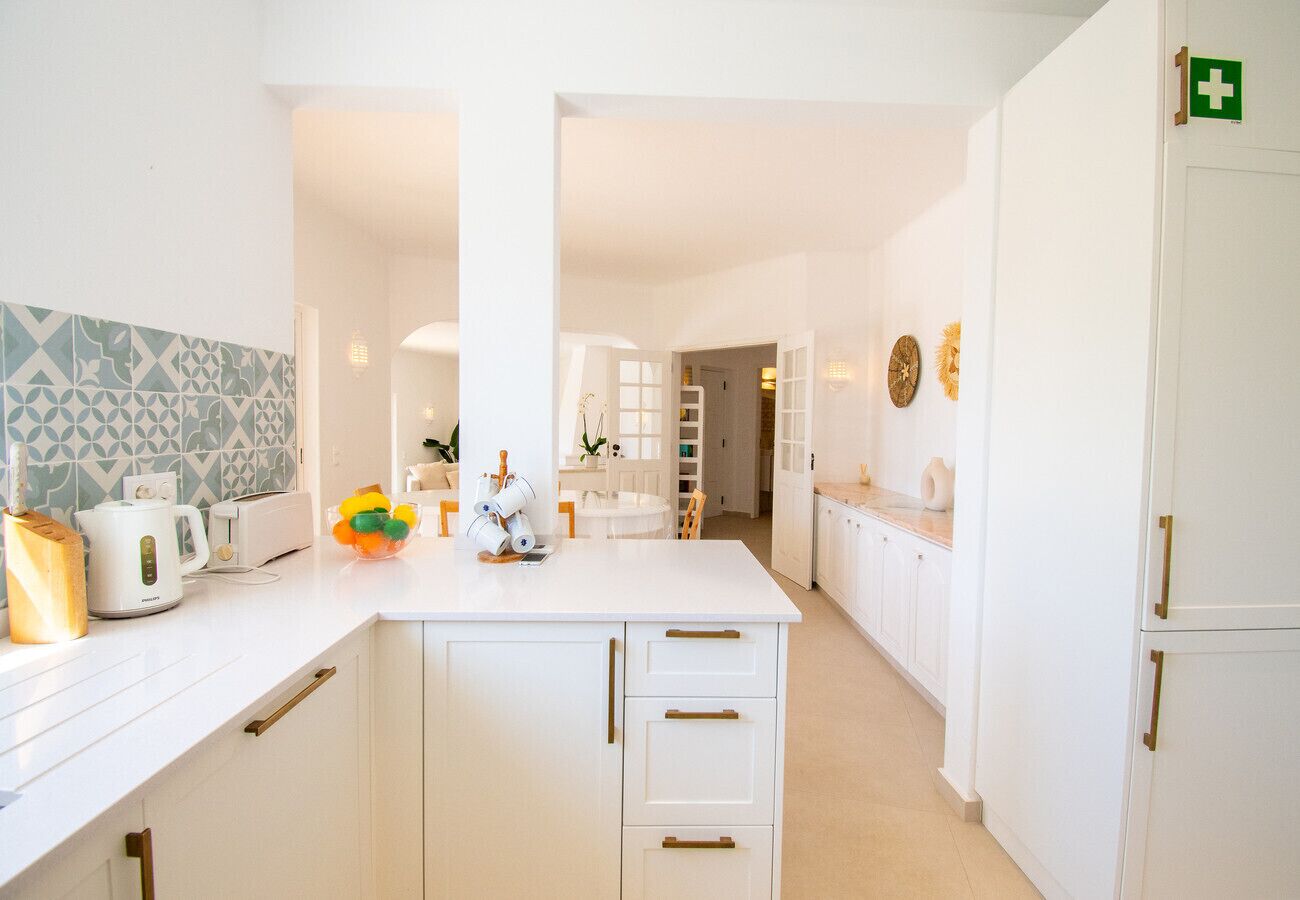 A modern kitchen with white cabinetry, a central island, and a visible emergency exit sign.