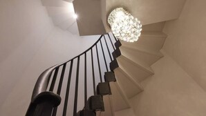 A spiral staircase with a modern design, featuring a unique light fixture at the top.