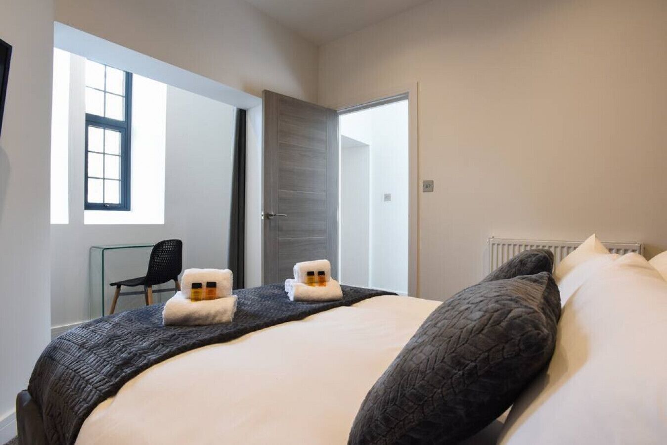 Ein Schlafzimmer mit einem großen Bett, zwei Handtüchern auf dem Bett, einem Sessel und einem Fenster.