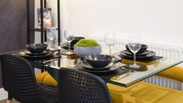 A dining table set with black bowls, wine glasses, and a green bowl centerpiece.