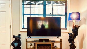 Un salon avec un téléviseur, une cheminée et des sculptures d’ours.