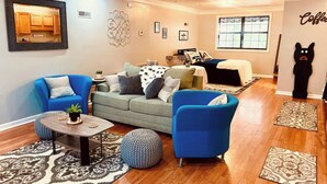 Un salon comprenant un canapé, deux fauteuils, une table basse et un ventilateur de plafond.