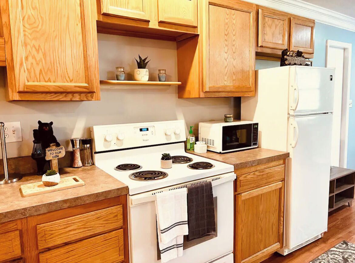 Una cucina con mobili in legno, un piano cottura bianco, un forno a microonde e un frigorifero.