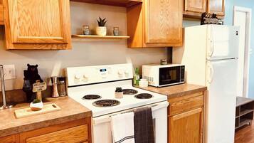 Una cucina con mobili in legno, un piano cottura bianco, un forno a microonde e un frigorifero.