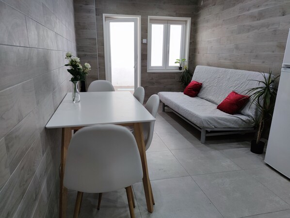A modern kitchen with a white table and chairs, a grey sofa with red cushions, and a window with a view. - Torre dos Clérigos Apartment
Near all of Porto's major attractions! (Porto)