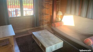 A cozy room with a bed, a table, and a lamp. - Studio Meublé Pour Saisonnier (Auriolles)