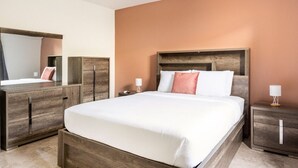 A hotel room with a large bed, wooden headboard, a nightstand with a lamp, and a wardrobe.