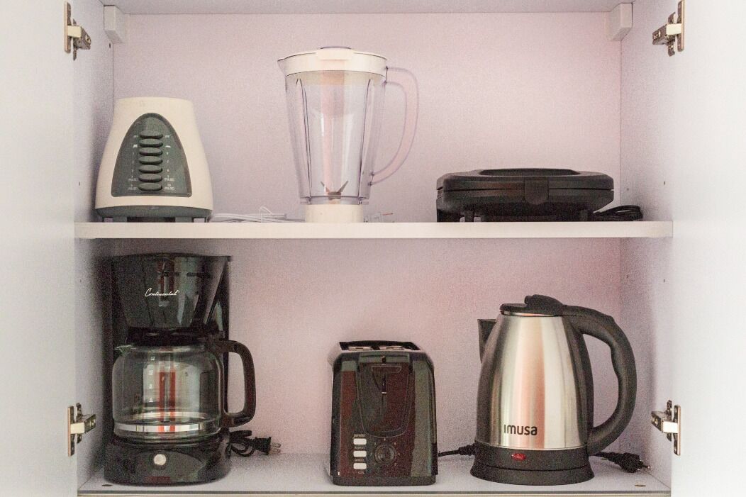 A kitchen with a coffee maker, toaster, blender, and electric kettle on the countertop.
