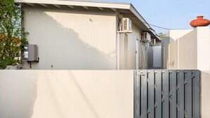 A modern building with a grey gate, a small air conditioning unit, and a chimney.