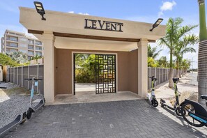Une entrée fermée par un portail, sur laquelle on peut lire l’inscription « LEVENT », et des trottinettes électriques garées à proximité.